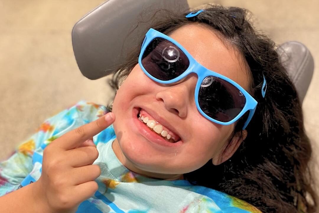 Smiling girl with blue glasses.